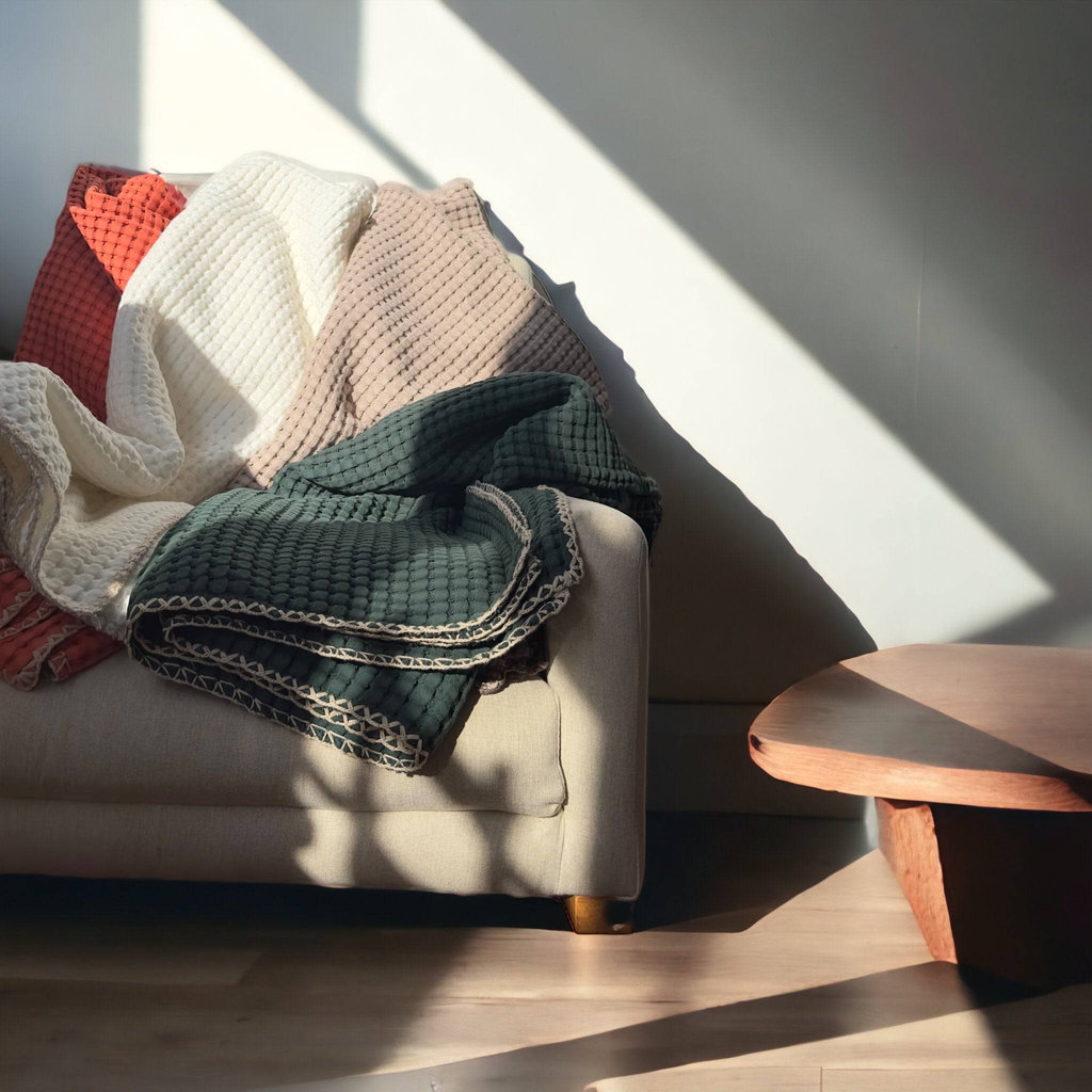An inviting display of premium throw blankets in soft, textured fabrics, beautifully draped in warm neutral tones, showcasing comfort and elegance for your home.