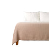 Beige waffle throw blanket on bed
